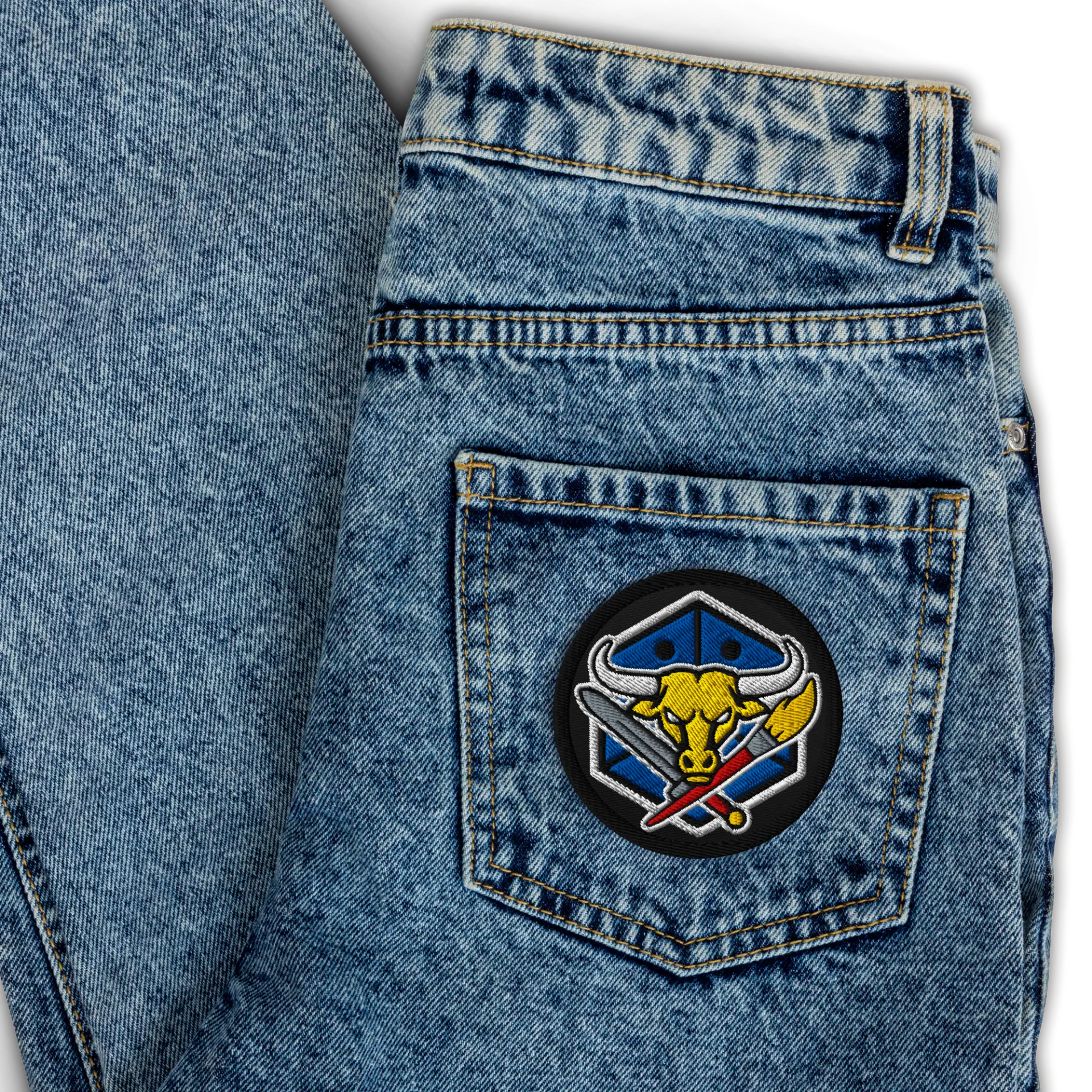 Circular embroidered Battle & Brush club patch sewn onto a denim back pocket